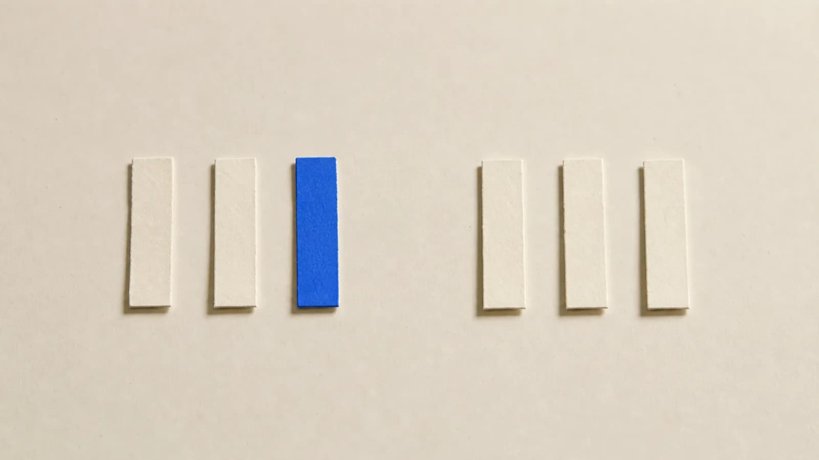 Paper strips lined up side by side on a paper surface, one place in the middle left empty and the gap still holding its position in the row
