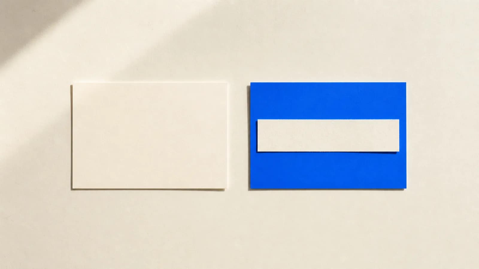 Two cards side by side on a cream paper background: the left one empty, the right one cobalt blue with a thin paper strip laid across it.