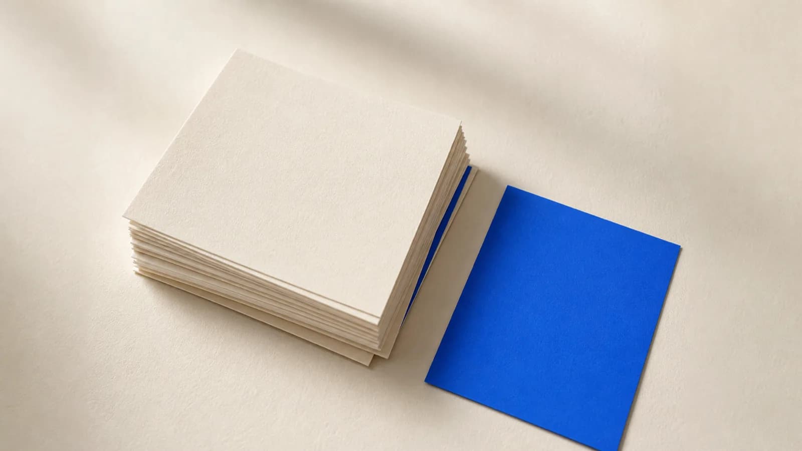 A thin card pushed under a stack of cream cards shows only its edge, while a cobalt blue card lies out in the open on top.