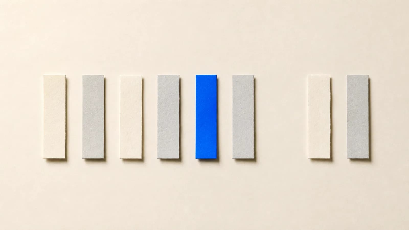Paper strips laid out left to right on an off white surface, with a gap among them and one strip in cobalt blue