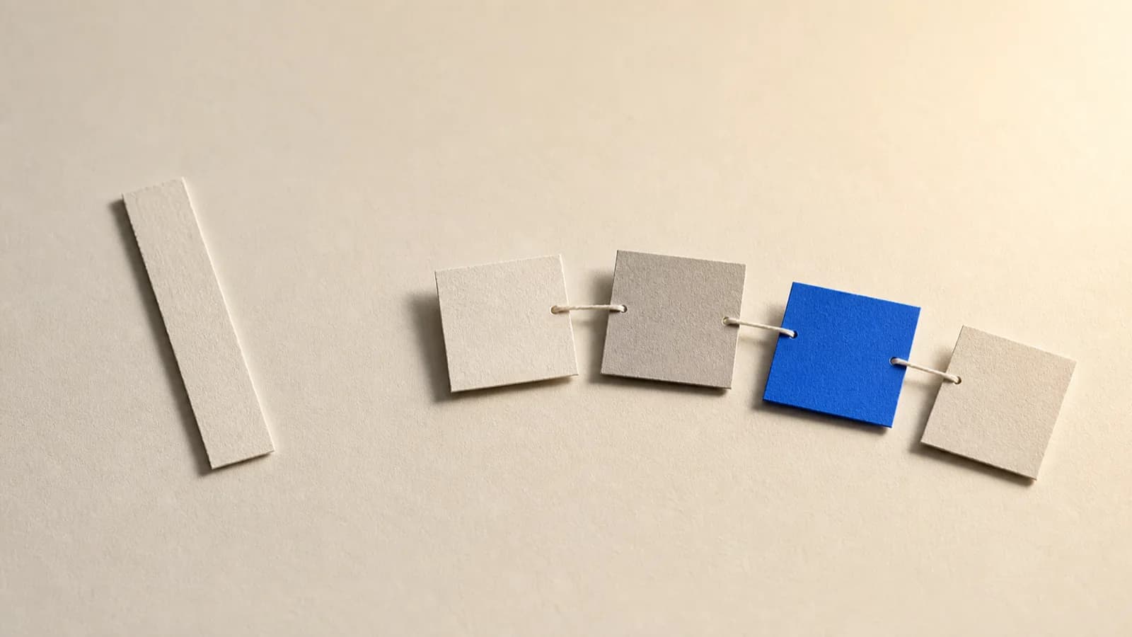 A long paper list next to several cards tied to one another with string, one of the tied cards in cobalt blue