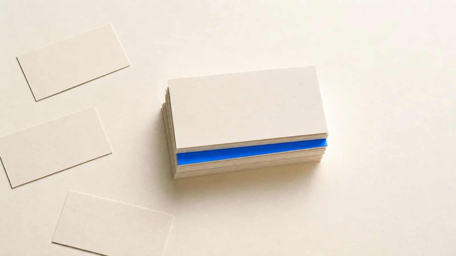 A few cards set aside at the edge of a central stack of cards on a paper surface, one card in the stack cobalt blue